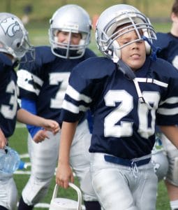 young kids on a football field wearing helmets