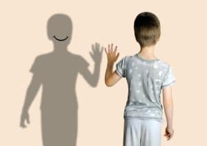 child 8-10 years old in gray t-shirt extended his hand to his shadow, concept imaginary friend, problems of loneliness, self-knowledge, psychology of childhood, personality development of teenager