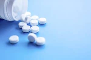 closeup white pills and bottle on blue background