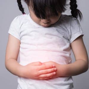 girl child abdominal pain on a gray background cross process